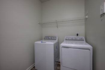 Two white front loading washing machines in a laundry room.