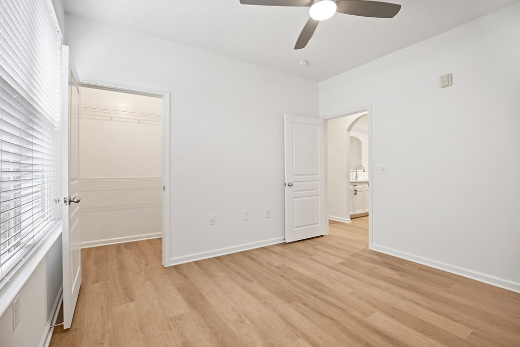 A room with a ceiling fan and wooden flooring.