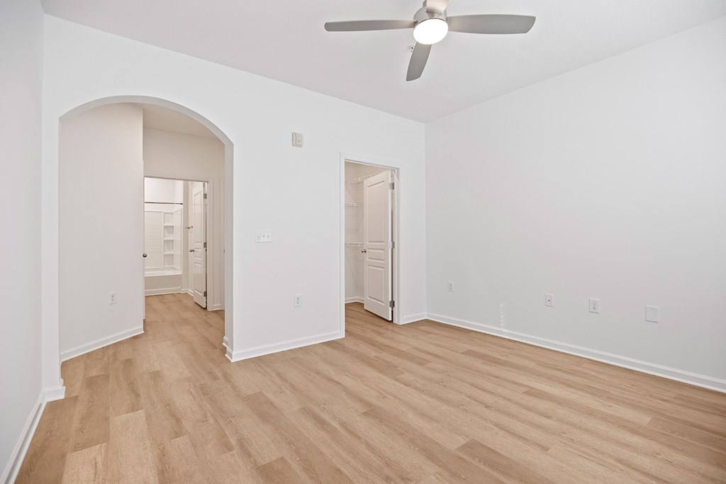 A room with a ceiling fan and wooden flooring.