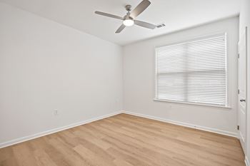 A room with a ceiling fan and a window with blinds.