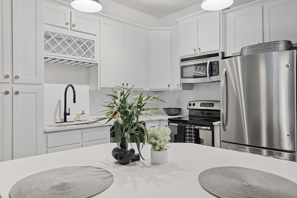 A modern kitchen with a stainless steel refrigerator and a white countertop.