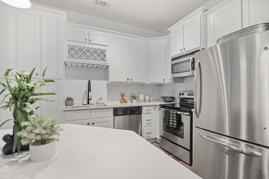 A kitchen with white cabinets and a stainless steel refrigerator.