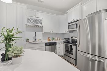 A kitchen with white cabinets and a stainless steel refrigerator.