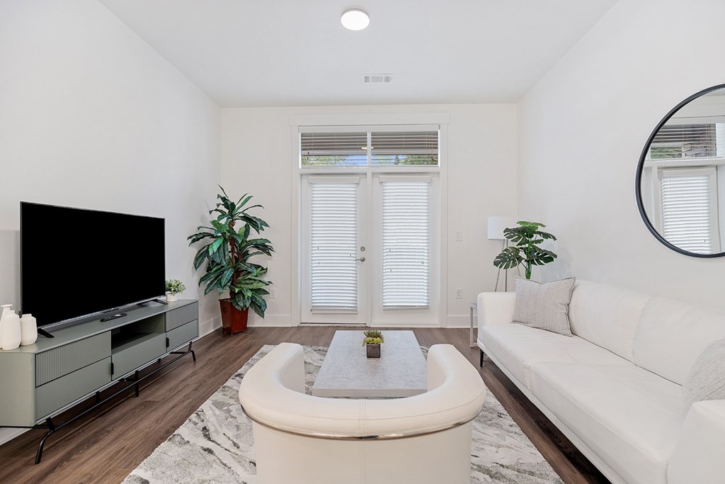 A living room with a white couch, a television, and a plant.
