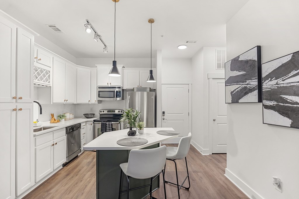 A modern kitchen with white cabinets and a wooden floor.