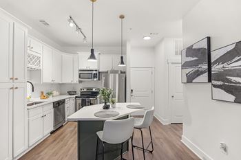 A modern kitchen with white cabinets and a black and white abstract painting on the wall.
