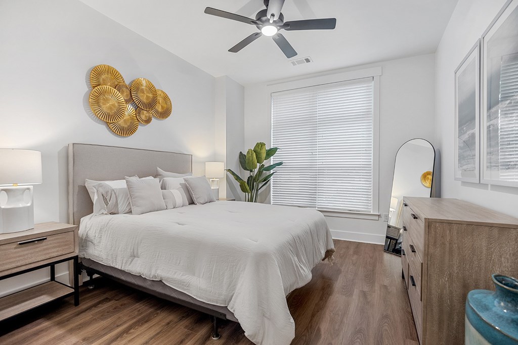 A bedroom with a bed, dresser, and ceiling fan.