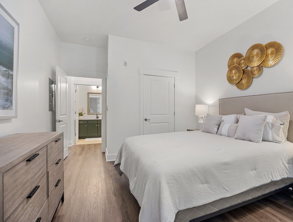 A bedroom with a bed, dresser, and ceiling fan.