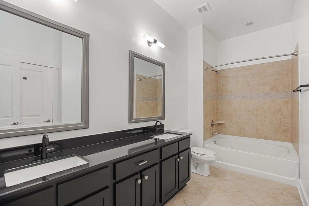 A bathroom with a white tub, sink, and mirror.