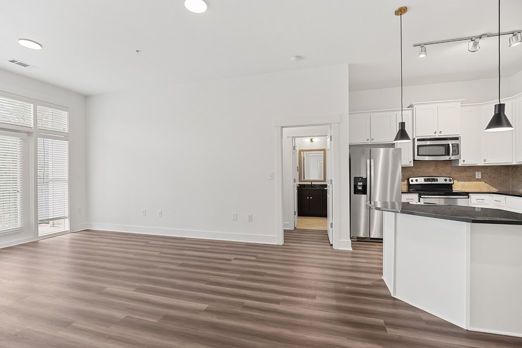 A kitchen with white cabinets and a wooden floor.