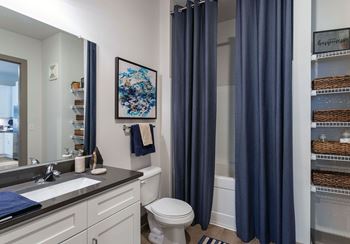 A bathroom with a toilet, sink, and blue curtains.