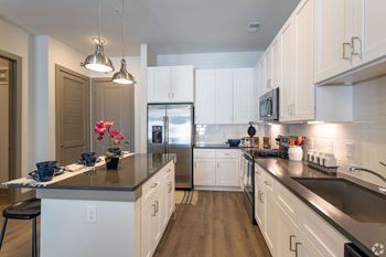 A kitchen with white cabinets and a black counter top.