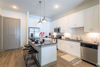A kitchen with white cabinets and a large island with bar stools.