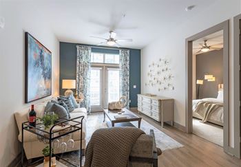 A living room with a couch, a chair, a coffee table, and a painting on the wall.