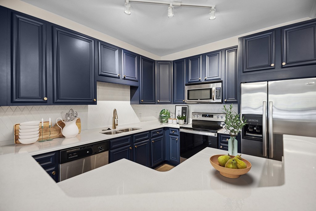 A modern kitchen with dark blue cabinets and stainless steel appliances.