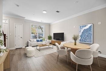 A living room with a white couch, a wooden coffee table, and a large painting on the wall.
