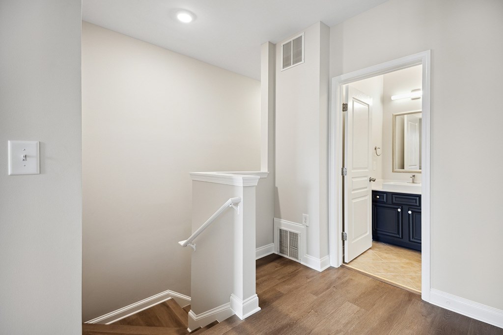 A white staircase with a landing in a room with a light switch on the wall.