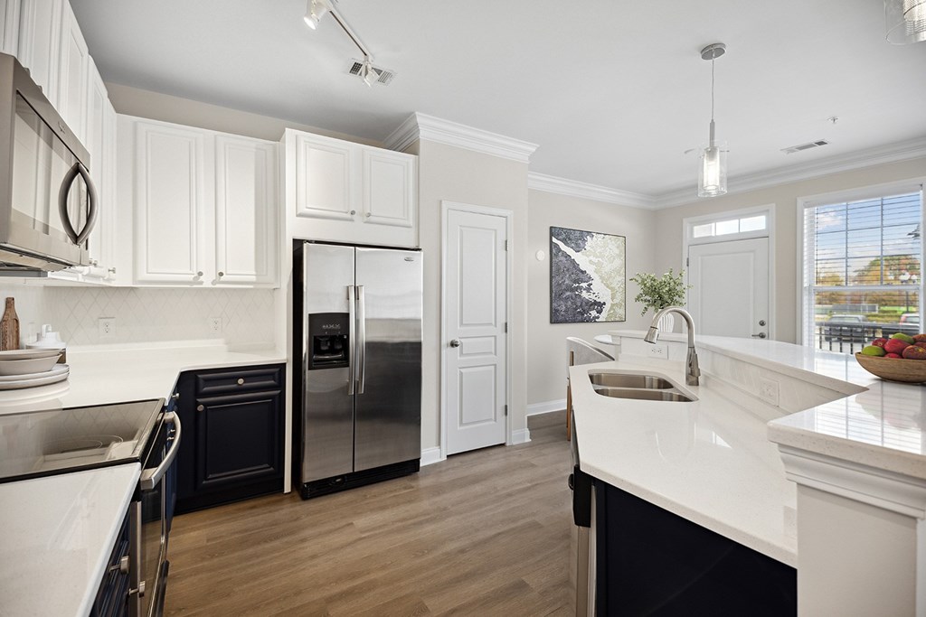 A modern kitchen with white cabinets and a black refrigerator.