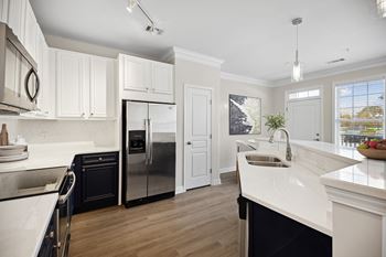 A modern kitchen with white cabinets and a black refrigerator.