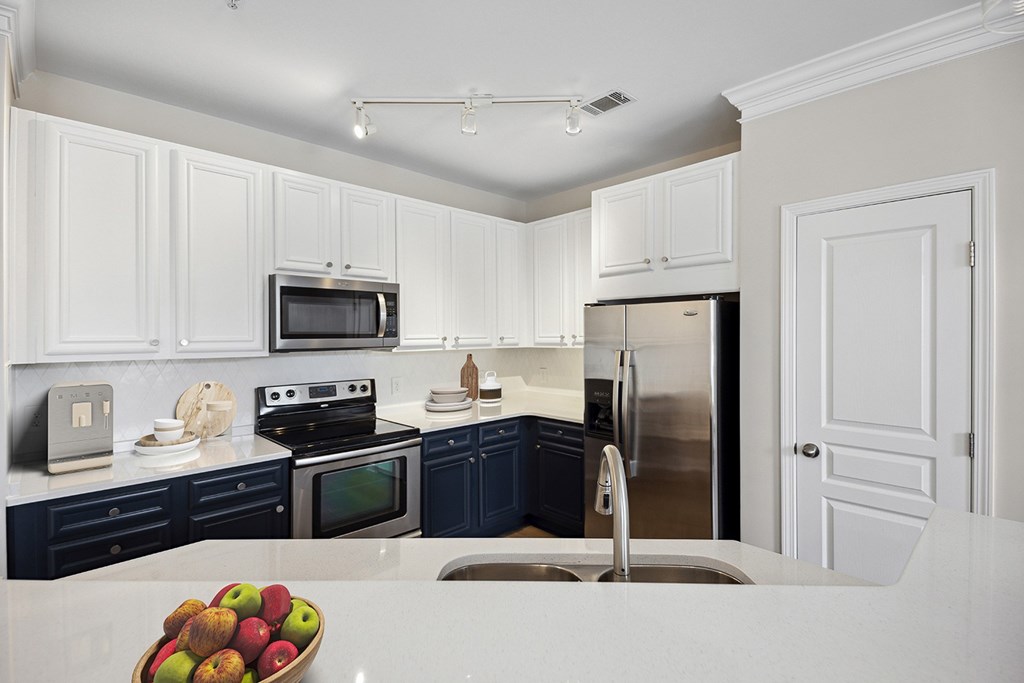 A kitchen with white cabinets and a bowl of apples on the counter.