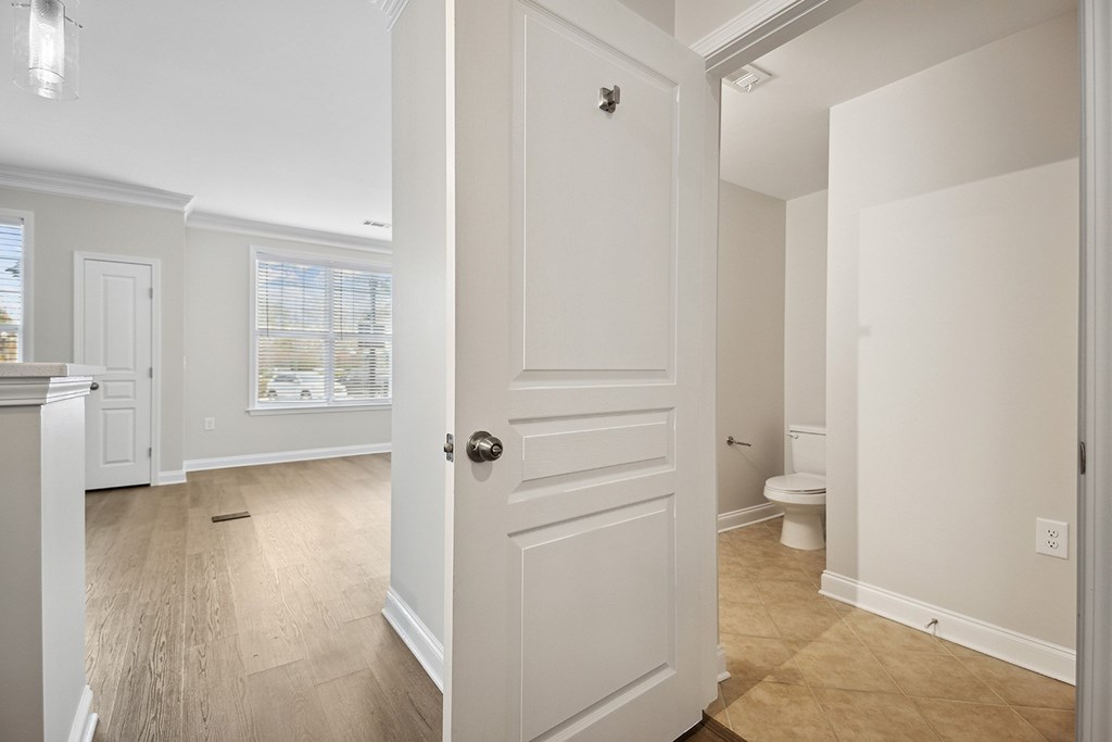 A white door is open to a room with a toilet.