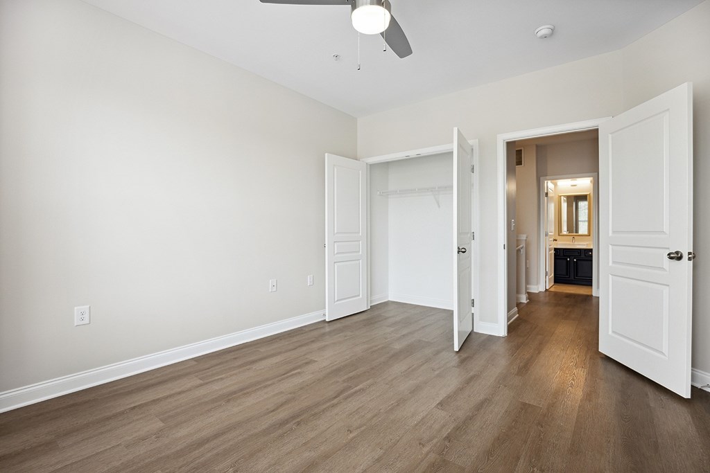 A room with a ceiling fan and light, and a doorway leading to another room.