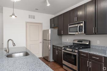 A kitchen with a granite countertop and stainless steel appliances.