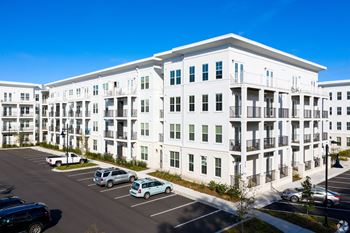 A white apartment building with a parking lot in front.