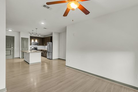 A room with a ceiling fan and a kitchen area.