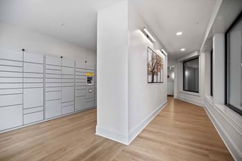 A long hallway with a white wall and a brown floor.