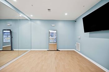 A room with a wooden floor and a wall-mounted television.