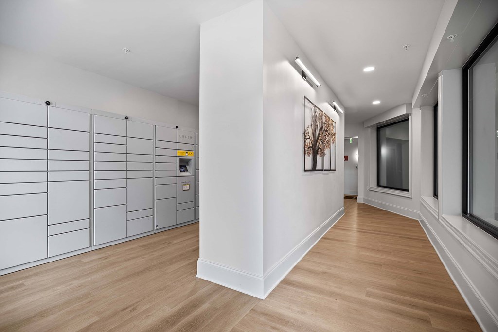 A long hallway with a white wall and a brown floor.