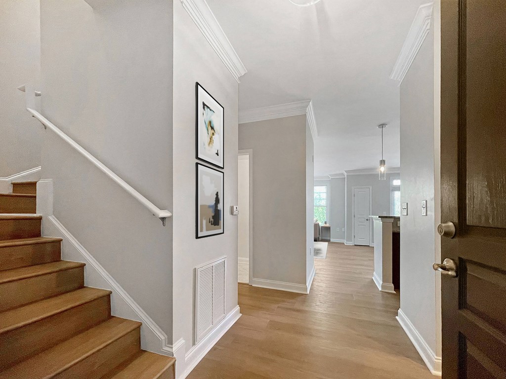 A hallway with a staircase and a doorway leading to another room.