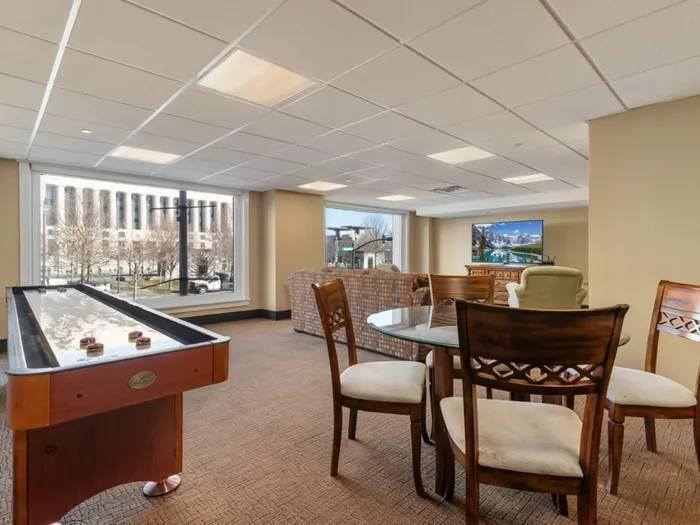 A room with a pool table, chairs, and a television.