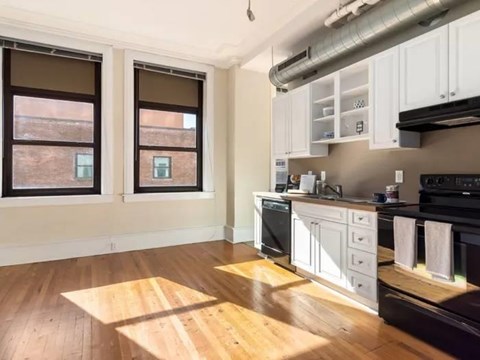 A kitchen with white cabinets and wooden floors.