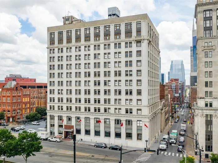 A street view of a city with a large white building in the middle.