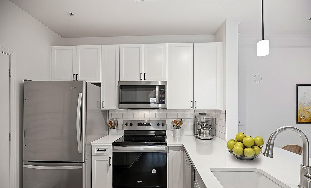 A modern kitchen with a stainless steel refrigerator and a black stove top oven.