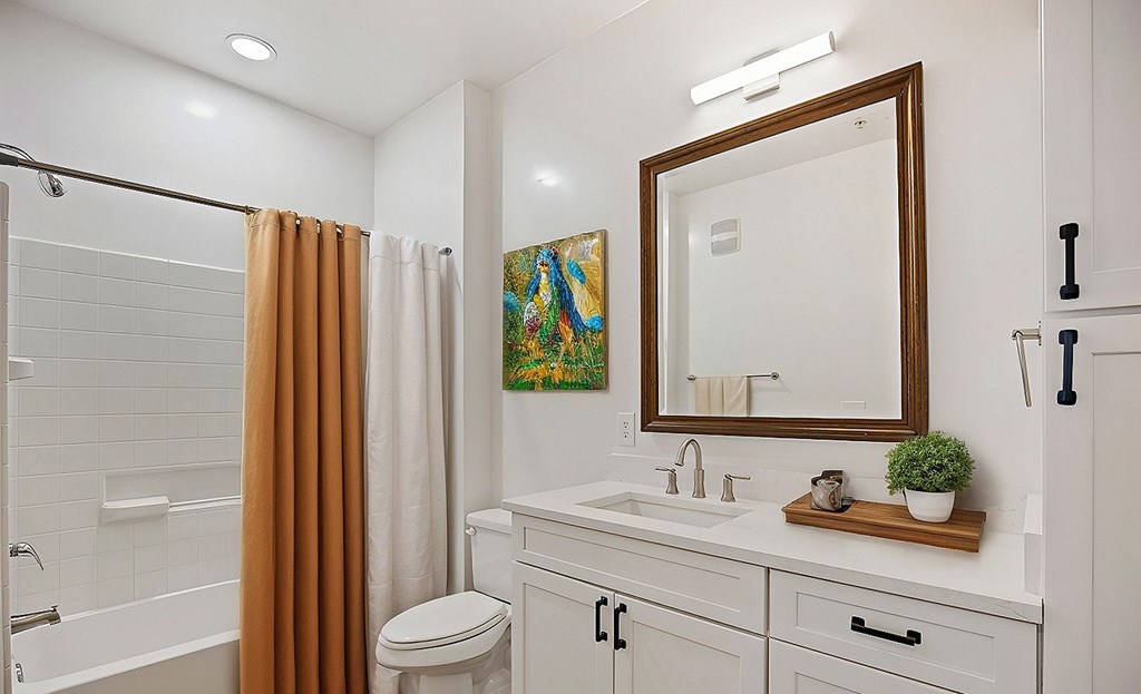 A bathroom with a white toilet, sink, and a brown shower curtain.
