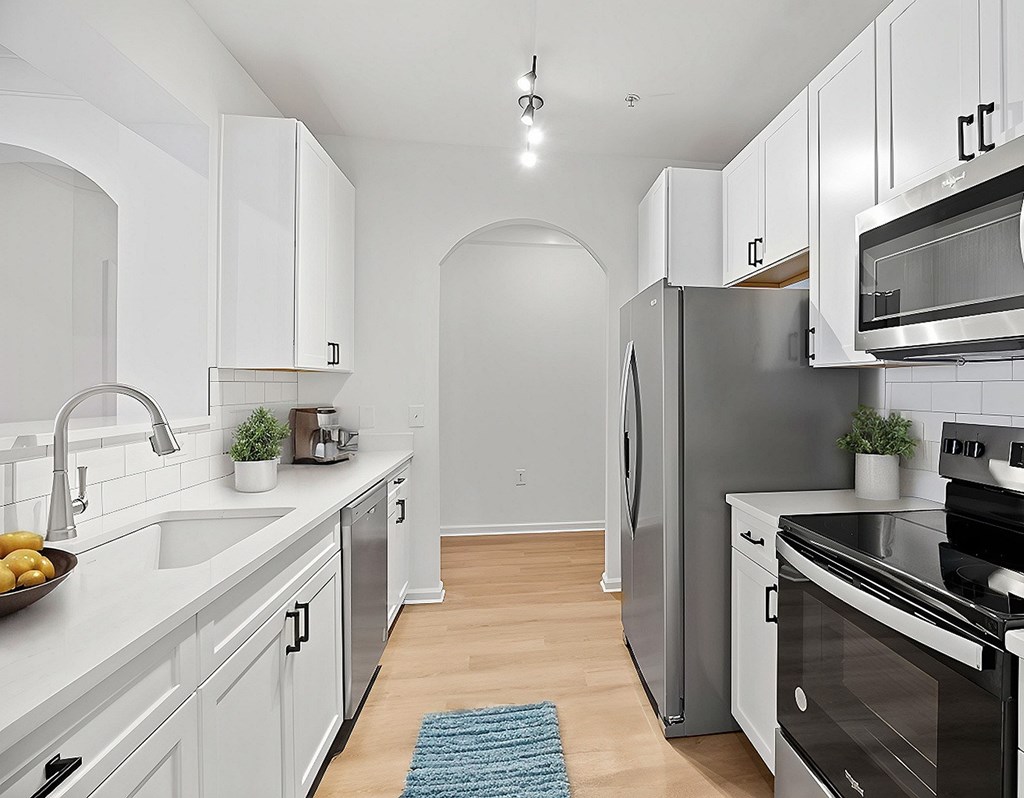 A kitchen with white cabinets and a blue rug on the floor.