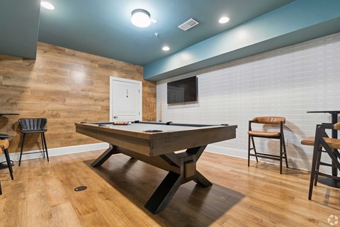 A pool table is in the middle of a room with a wooden floor and a white door.