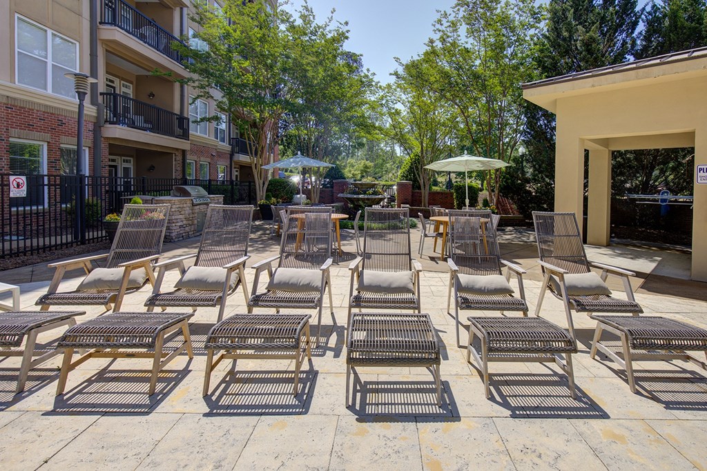 A patio with chairs and tables is surrounded by trees and buildings.