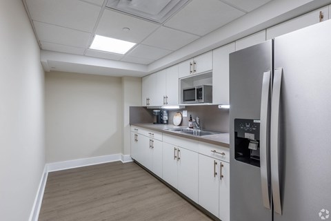 A kitchen with a refrigerator, microwave, and sink.
