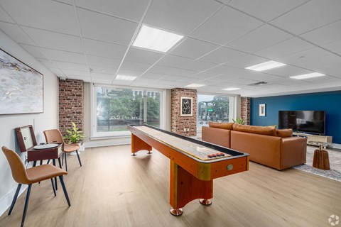 A room with a pool table and chairs.