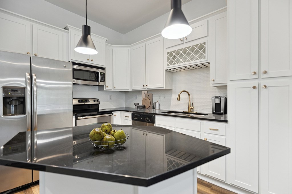 A modern kitchen with a black granite countertop and stainless steel appliances.