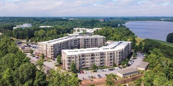A large building with the words "Veterans Landmark" on the top is surrounded by trees and has a parking lot in front.