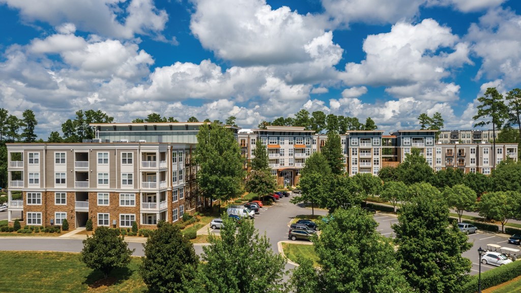 A large apartment complex with a parking lot in front.