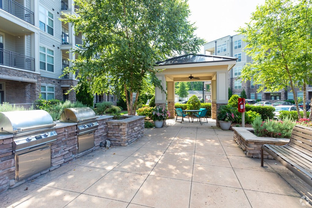 A patio with a gazebo, benches, and a fire pit.