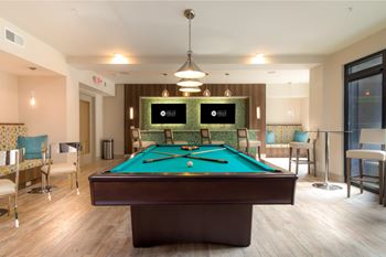 A pool table in a room with chairs and a TV.