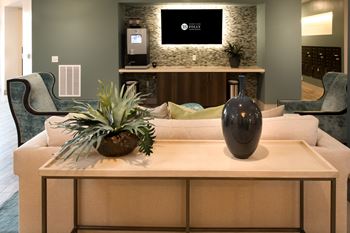 A living room with a white couch, a wooden coffee table, and a TV mounted on the wall.
