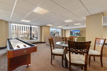 A room with a pool table, chairs, and a television.